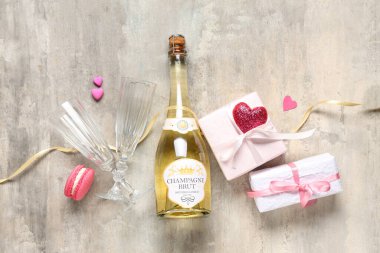 Gözlüklü bir şişe şampanya, hediye kutuları ve gri grunge arka planda dekor. Sevgililer Günü kutlaması