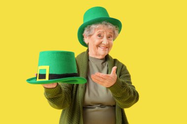 Sarı arka planda cüce şapkalı mutlu son sınıf kadını. Aziz Patrick Günü kutlaması