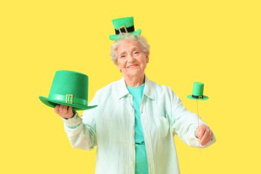 Sarı arka planda Aziz Patrick Günü kutlamaları için cüce şapkalı mutlu yaşlı kadın.