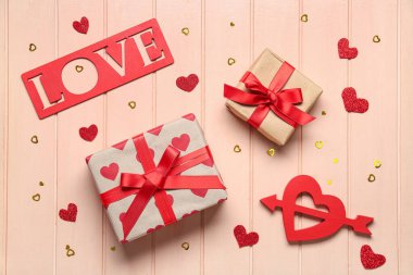 Aşk kelimesi hediye kutuları ve ahşap arka planda kalpler. Sevgililer Günü kutlaması