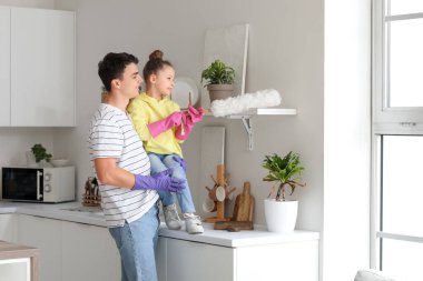 Genç baba ve kızı, mutfakta birlikte toz bezi temizliyorlar.