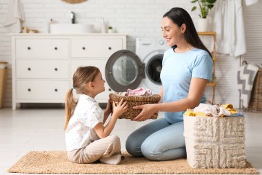 Genç bir kadın ve iki sepet dolusu çamaşırları olan küçük kızı.