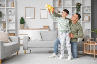 Sevimli küçük çocuk ve babası evde uçakla oynuyorlar.