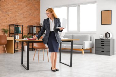 İş yerinin yakınında dizüstü bilgisayarı olan kadın muhasebeci.