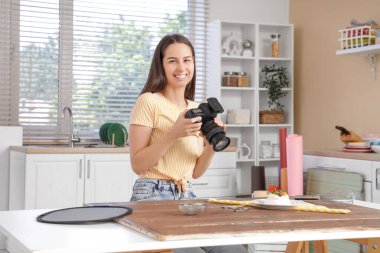 Genç bayan fotoğrafçı mutfakta yemek fotoğrafı çekiyor.