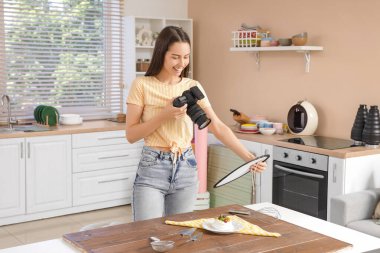 Genç bayan fotoğrafçı mutfakta yemek fotoğrafı çekiyor.