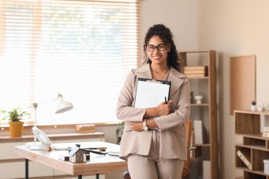 Female African-American lawyer with clipboard in office clipart