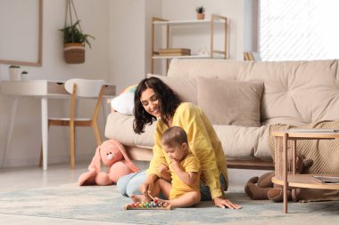 Güzel, genç, mutlu bir anne ve evde ksilofonla oynayan tatlı bir bebek.