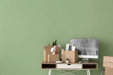 Taşındığı gün, iş yerinde paket bilgisayar monitörü ve yeşil duvarın yanındaki kutular.