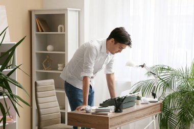 Masanın yanında antika daktilosu olan genç bir yazar.