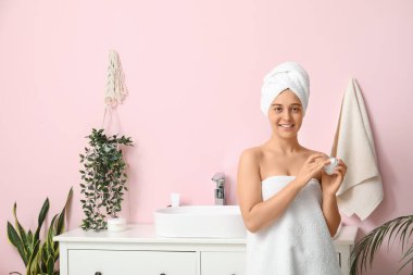 Güzel genç bir kadının banyoda yüz kremi sürdüğü bir sabah.