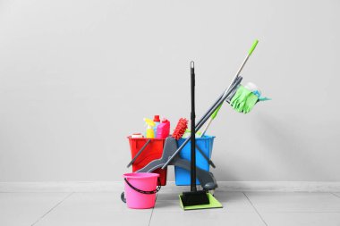 Gri duvarın yanında temizlik malzemeleri olan bir tramvay.