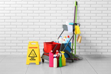 Beyaz tuğla duvarın yanında kapıcı arabası olan uyarı levhası.