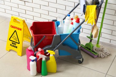 Beyaz tuğla duvarın yanında kapıcı arabası olan uyarı levhası.