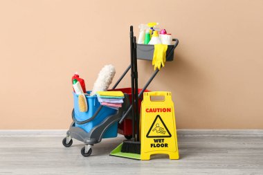 Temizlik malzemeleri ve bej duvarın yanında uyarı levhası olan bir araba.