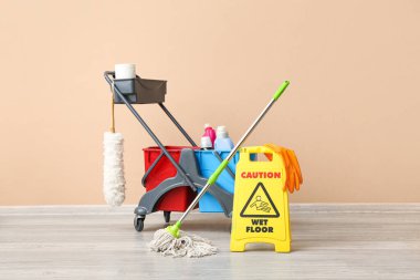 Kapıcının arabası ve uyarısı bej duvarın yanında.