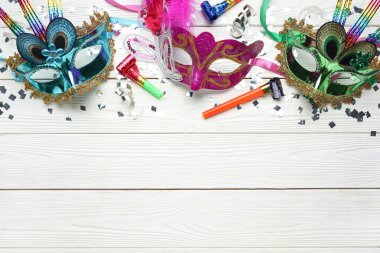 Parti boynuzları ve beyaz ahşap arka planda konfeti olan güzel karnaval maskeleri. Üst görünüm