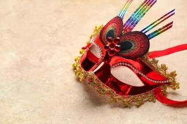 Bej arka planda güzel bir kırmızı karnaval maskesi. Yakın çekim.