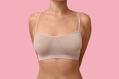 Pembe arka planda bej bluzlu genç bayan, yakın plan.