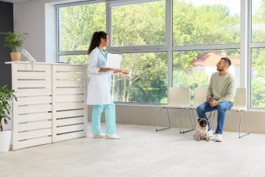 Klinikte sahibi ve köpeği olan Afro-Amerikalı bir veteriner.