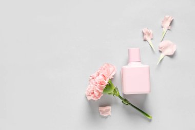 Bir şişe parfüm, karanfil çiçeği ve beyaz arka planda taç yaprakları.