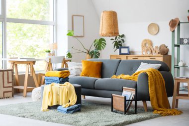 Gri kanepesi ve pouf üzerinde temiz giysileri olan şık bir oturma odası.