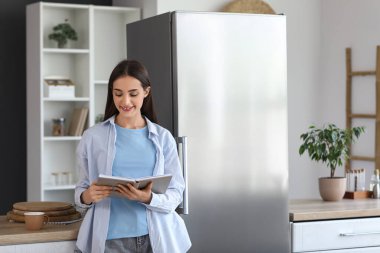 Mutfakta bir fincan kahve okuyan güzel, genç ve mutlu bir kadın.