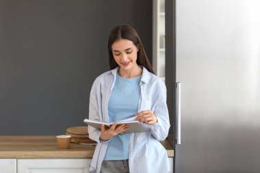 Mutfakta bir fincan kahve okuyan güzel, genç ve mutlu bir kadın.