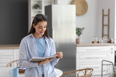 Mutfakta çay fincanı okuyan güzel, genç ve mutlu bir kadın.