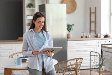 Mutfakta çay fincanı okuyan güzel, genç ve mutlu bir kadın.