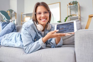 Tablet bilgisayarlı kadın turist kanepede yatıyor. Çevrimiçi rezervasyon kavramı