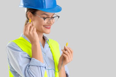 Kadın inşaatçı hafif arkaplana kulak tıkaçları yerleştiriyor