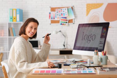 Ofiste grafik tableti ve bilgisayarla çalışan genç bayan tasarımcı.