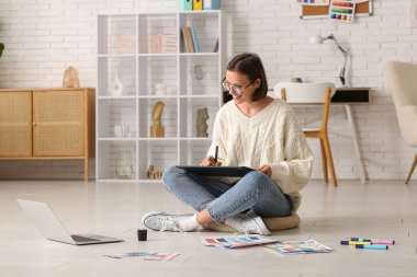 Ofiste renk örnekleri, tablet bilgisayar ve dizüstü bilgisayarla çalışan genç bayan grafik tasarımcısı.
