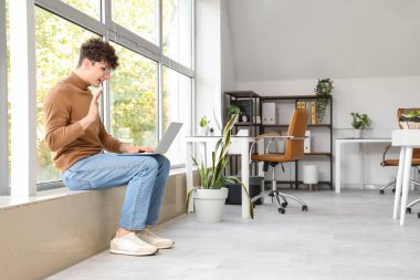 Bilgisayarlı genç adam ofiste video sohbeti yapıyor.