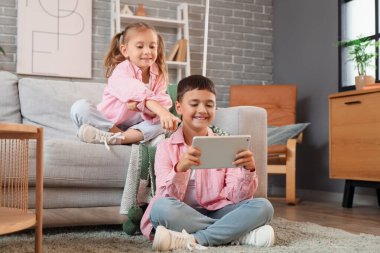 Evde video oyunu oynayan tabletli şirin, mutlu çocuklar.