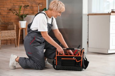 Mutfakta buzdolabını tamir eden kadın işçi.