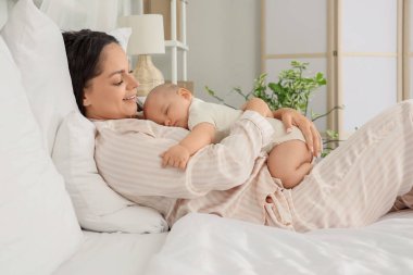 Anne ve uyuyan bebeği yatak odasında yatıyor.