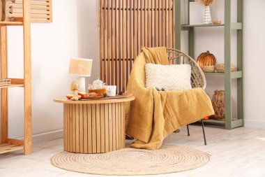 Oturma odasının içinde lamba, çaydanlık, çay ve koltuk olan kahve masası.