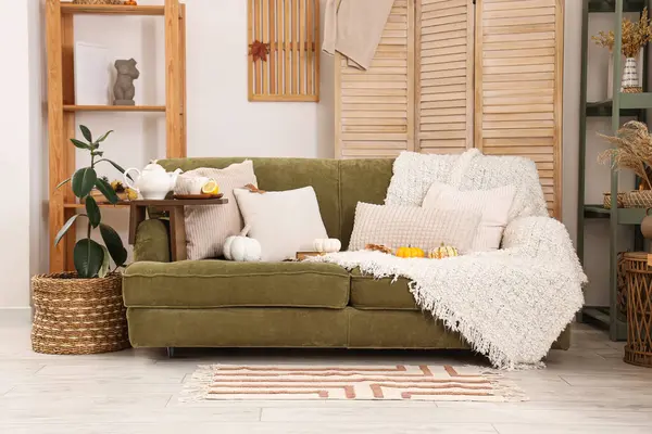 Çaydanlık ve bir fincan yeşil çay oturma odasındaki kanepede.