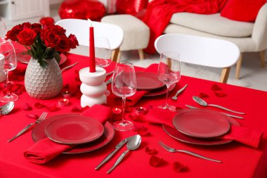 Sevgililer Günü için hazırlanmış şölen masası kırmızı güller ve evde yanan mumlarla süslenmiş.