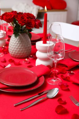 Sevgililer Günü için hazırlanmış şölen masası kırmızı güller ve evde yanan mumlarla süslenmiş.