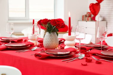 Sevgililer Günü için hazırlanmış şölen masası kırmızı güller ve evde yanan mumlarla süslenmiş.