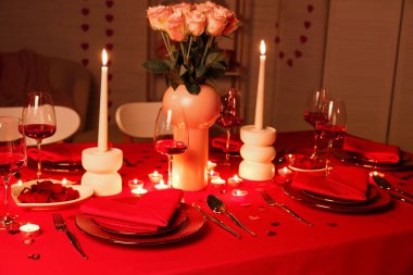 Akşamki Sevgililer Günü kutlaması için yemek masası, yanan mumlar ve pembe güller.