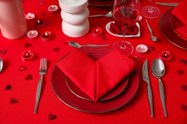 Sevgililer Günü kutlaması için yemek masası, mumlar ve kağıt kalpler.