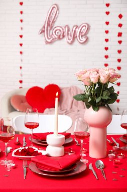 Sevgililer Günü için evde pembe güller ve mumlarla süslenmiş masa.