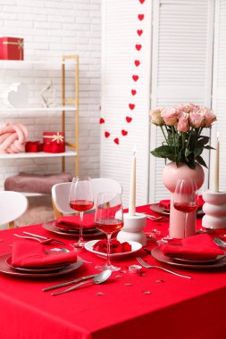 Sevgililer Günü için evde pembe güller ve mumlarla süslenmiş masa.