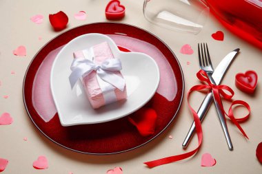 Sevgililer Günü için güzel bir masa. Bej arka planda şarap şişesi, hediye ve dekor var.