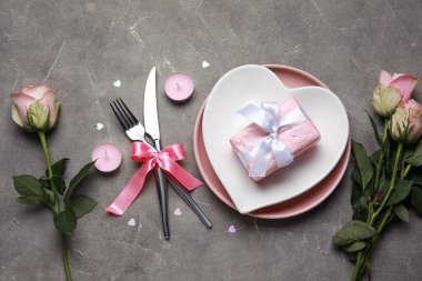 Sevgililer Günü için güzel bir masa. Pembe güller, hediye ve gri arkaplanda mumlar.