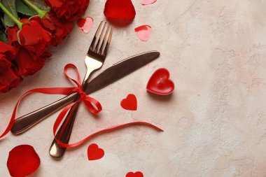 Sevgililer Günü için güzel çatal bıçak takımı. Kırmızı güller, mum ve bej arka planda kalpler.